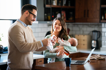 Cheerful young family with a baby child enjoying online purchasing on the internet at home