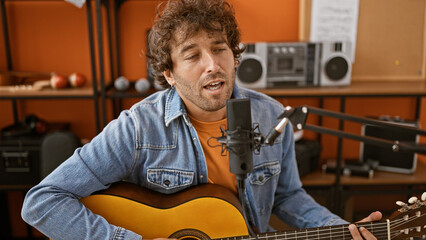 Hispanic man singing and playing guitar in a music studio