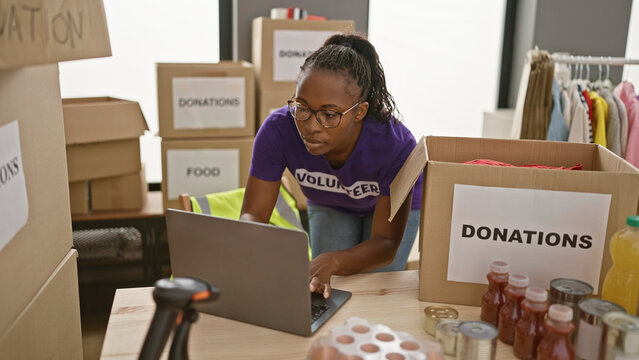 African american woman volunteers at donation center using laptop indoors