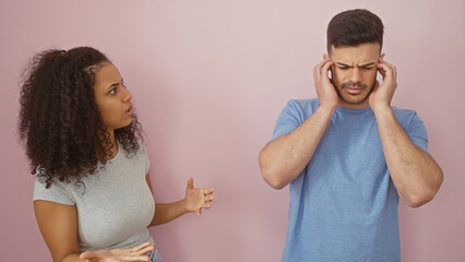 A woman gestures while talking to a frustrated man against a pink background.