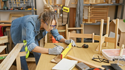 Focused woman measuring wood with level in a well-equipped carpentry workspace