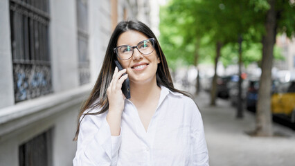 Young beautiful hispanic woman smiling happy speaking on the phone in the streets of Madrid