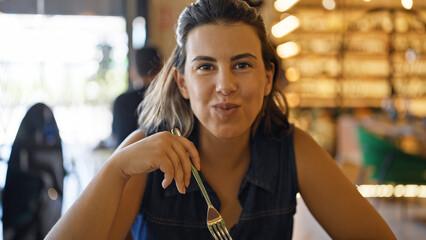 Young beautiful hispanic woman eating at the restaurant