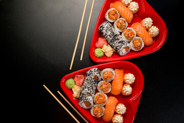 Two sets of sushi in the shape of a heart and two pairs of sushi sticks