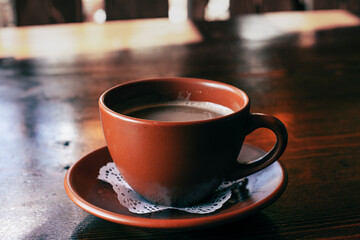 Fresh Americano coffee with milk in traditional  brown clay cup  on the wooden table