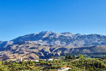 A town in the valley and rocky peaks in the Lefka Ori mountains on the island of Crete