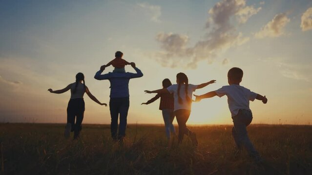 Family of four running in nature. Happy child daughter concept. Silhouette of a family running together in the big city. Silhouette of a family running through nature with lifestyle large children.
