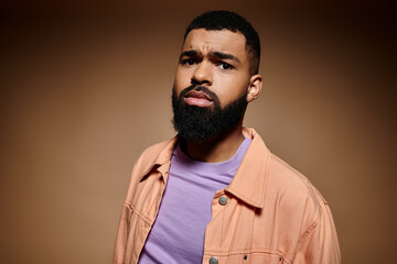 Handsome African American man with beard poses in vibrant orange jacket.