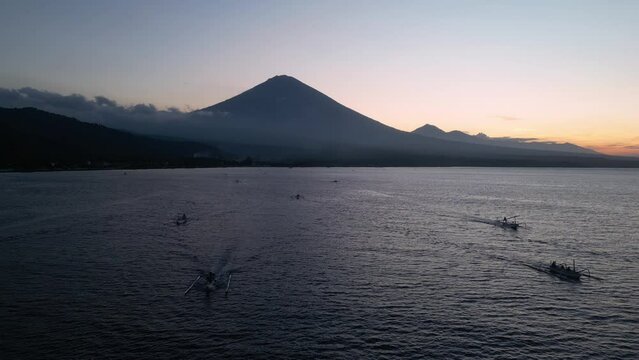 Amed, Bali: Aerial drone footage of the sunset over Gunung Agung volcano with traditional Jukung boat along the Bali north coast in Indonesia. 
