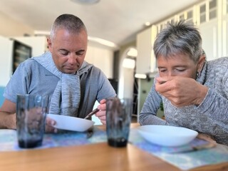 Young adult couple sitting at table, eating. Married couple eating at table. Family daily life. Portrait of happy young couple eating together at table, in cozy home