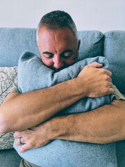 Young adult man sitting on sofa hugging pillow.Man talking to...