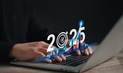 Businessman typing on a laptop with a virtual display showing a 2025 growth projection graph....