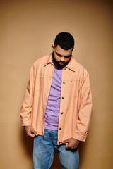 Handsome African American man in fashionable attire standing with hands in pockets in front of vibrant backdrop.