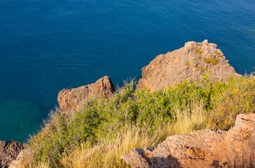 Large boulder rocks with vegetation along the coastline of the Mediterranean Sea in Antalya, Turkey