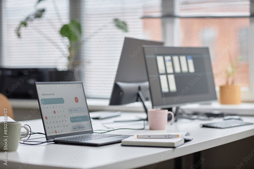 Poster side view shot in pastel colors of office workplace table with laptop displaying calendar page, note