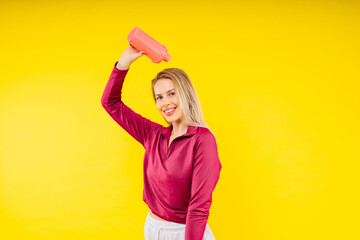 Studio fitness female portrait with bottle of water isolated on yellow background