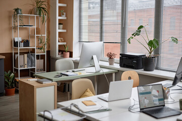 Shot of light cozy office interior in modern minimalistic style with working desks and plants, copy space