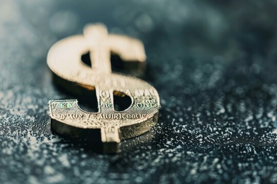 Closeup of a gold dollar symbol on a textured surface, conveying financial crisis or volatility