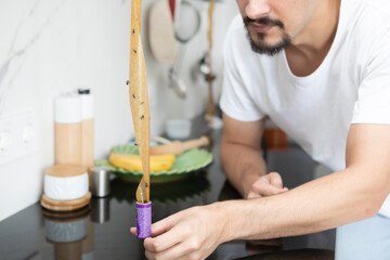 Young excited man discovers many flies on glued fly glue trap in the kitchen	