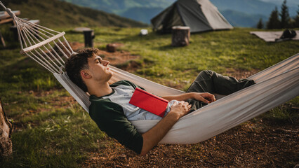 Young boy sleep in the hammock after read book on the mountain