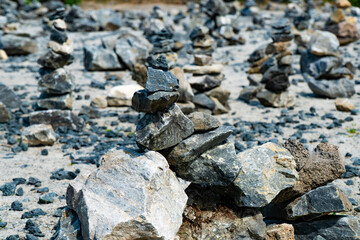 Close-up of a pile of stacked stones on a rocky terrain. The image captures the balance and arrangement of various rocks, showcasing the art of stone stacking in a natural outdoor setting.