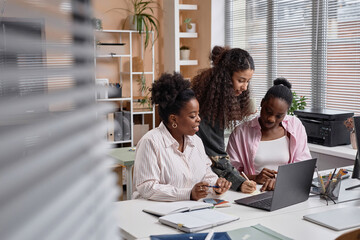 Obraz premium Diverse team of businesswomen collaborating writing notes on paper and discussion issues in office, copy space