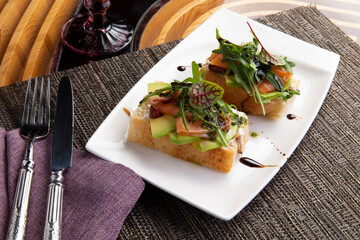 Bruschettas with avocado and salmon in a plate.