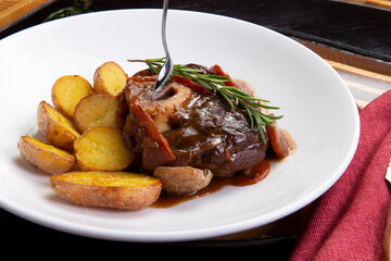 Osso buco with baked potatoes in a plate.