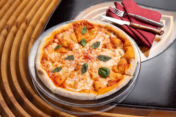 Pizza with cheese and basil in a plate.