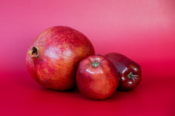 Red apples and pomegranate on a red background. Healthy food.
