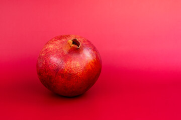 Ripe pomegranate fruit on a red background. Copy space.