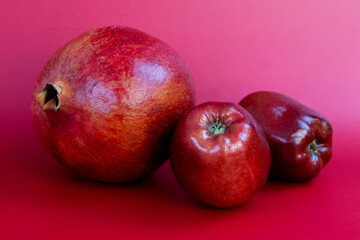 Ripe red apples and pomegranate on a pink background