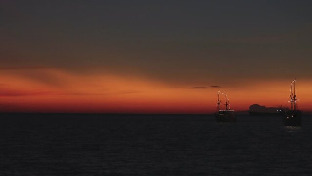 Time lapse of the silhouette of two phinisi boats against the background of the twilight sky