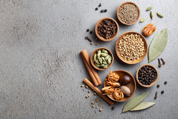 A variety of whole Indian spices in wooden bowls on a gray background with copyspace top view
