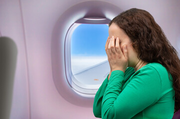 Close-up view of a woman covering her face and crying.Headache in the airplane, woman passenger...