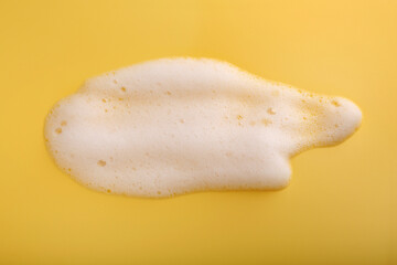 Sample of fluffy foam on yellow background, top view