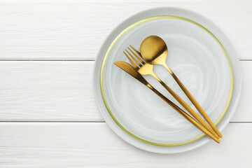 Stylish setting with cutlery and plate on white wooden table, top view. Space for text