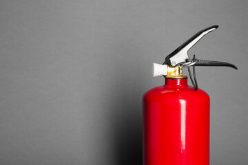 One red fire extinguisher on gray background, space for text