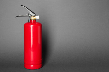 One red fire extinguisher on gray background, space for text