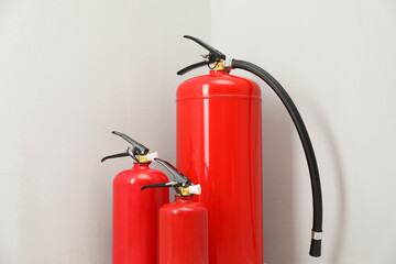 Three fire extinguishers near light grey wall