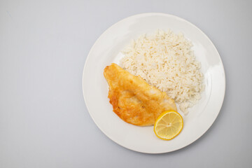 Fried fish fillets with rice and lemon on plate