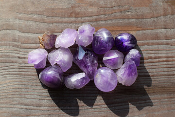 Beautiful natural amethyst crystals illuminated by sunlight on an old wooden background. Healing...