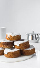 Iced mini bundt cakes on a white plate, vanilla bundlette with a clementine segment on a plate, small vanilla bundt cakes with an icing glaze
