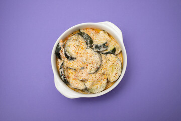 close-up baked zucchini baked with sauce in bowl