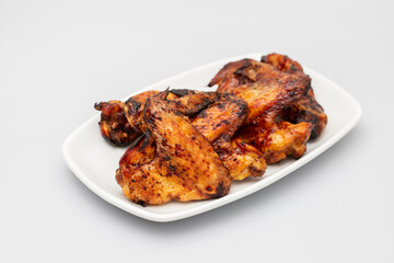 Baked chicken wings with sweet chili sauce in a plate.