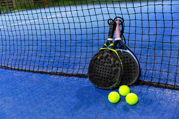 a pair of padel rackets on a padel court with a yellow ball