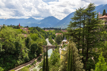 River passer promenade in Merano with mountain panorama and bridge, South Tyrol, Italy