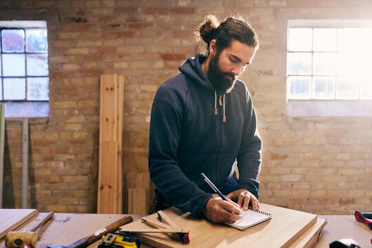 Carpenter sketching designs at a workshop bench