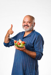 Senior Indian asian man eating fresh salad. Mature male having healthy snack, healthcare, diet concept.