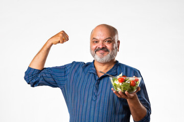 Senior Indian asian man eating fresh salad. Mature male having healthy snack, healthcare, diet...